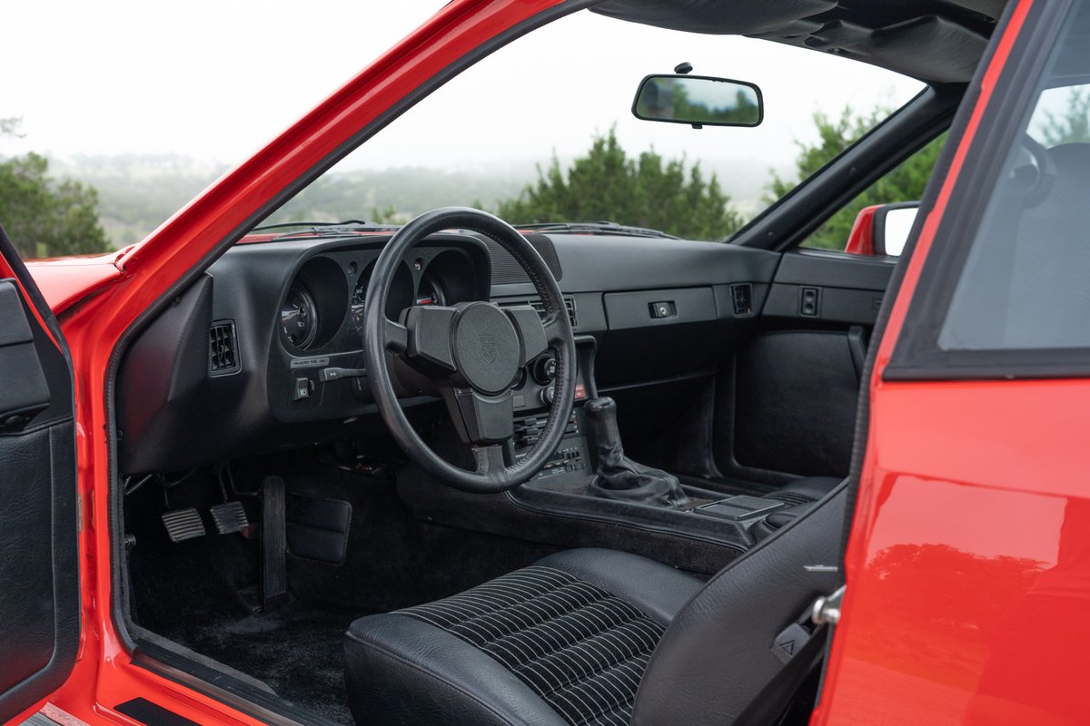 Interior of a Guards Red 1981 Porsche 924 Turbo, featuring black leather seats and a manual transmission shifter.