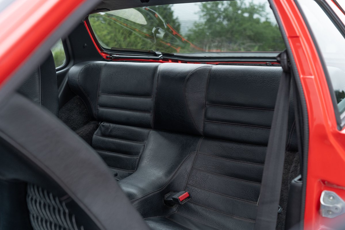 Interior view of a 1981 Guards Red Porsche 924 Turbo's black leather rear seats.
