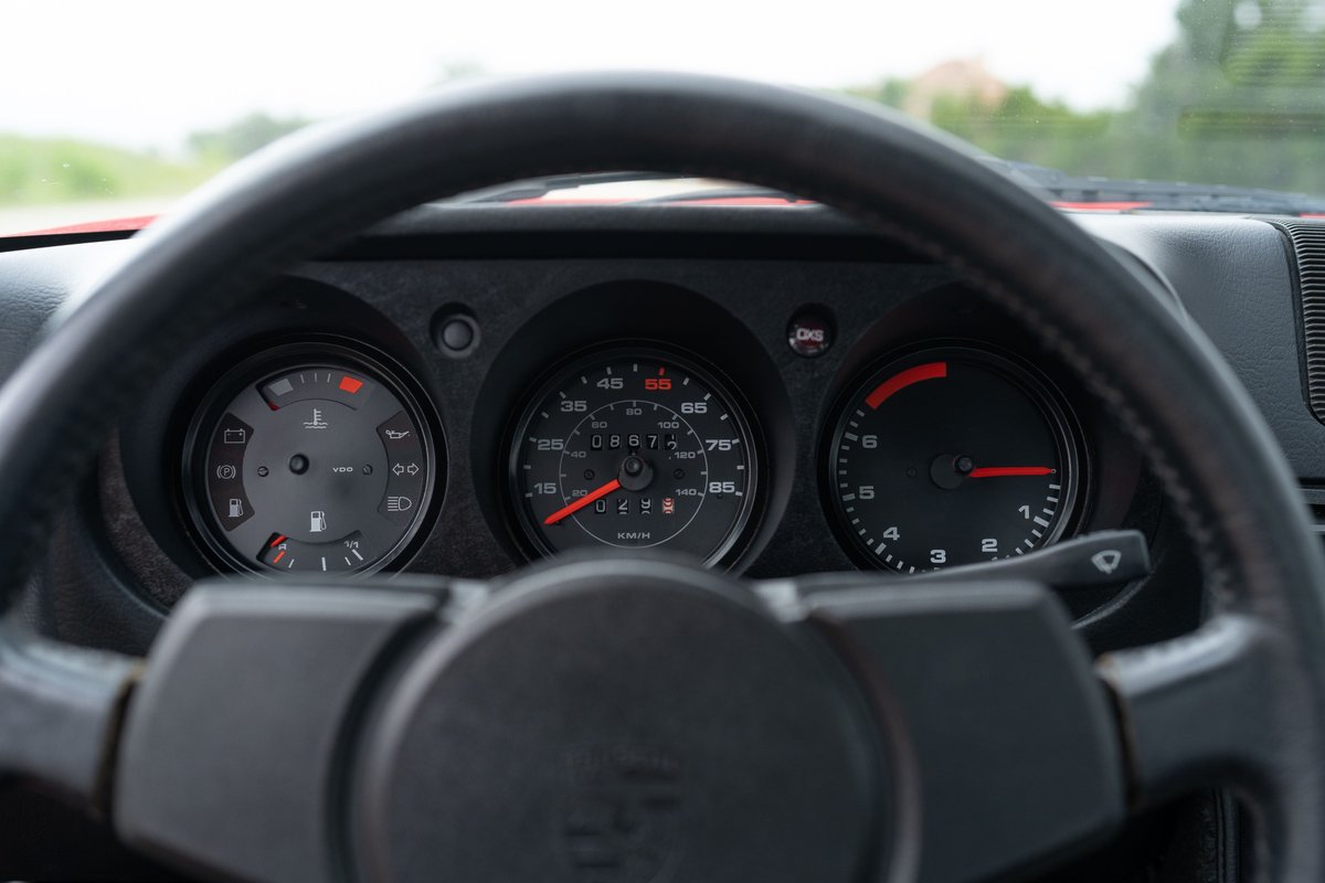 Interior of a Guards Red 1981 Porsche 924 Turbo, showing the dashboard gauges and steering wheel.