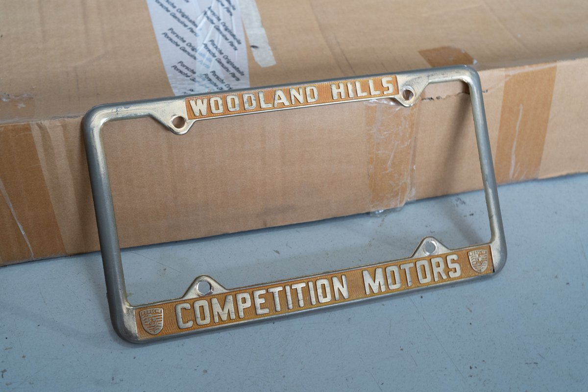Porsche license plate frame from Competition Motors Woodland Hills, with gold trim and crests.
