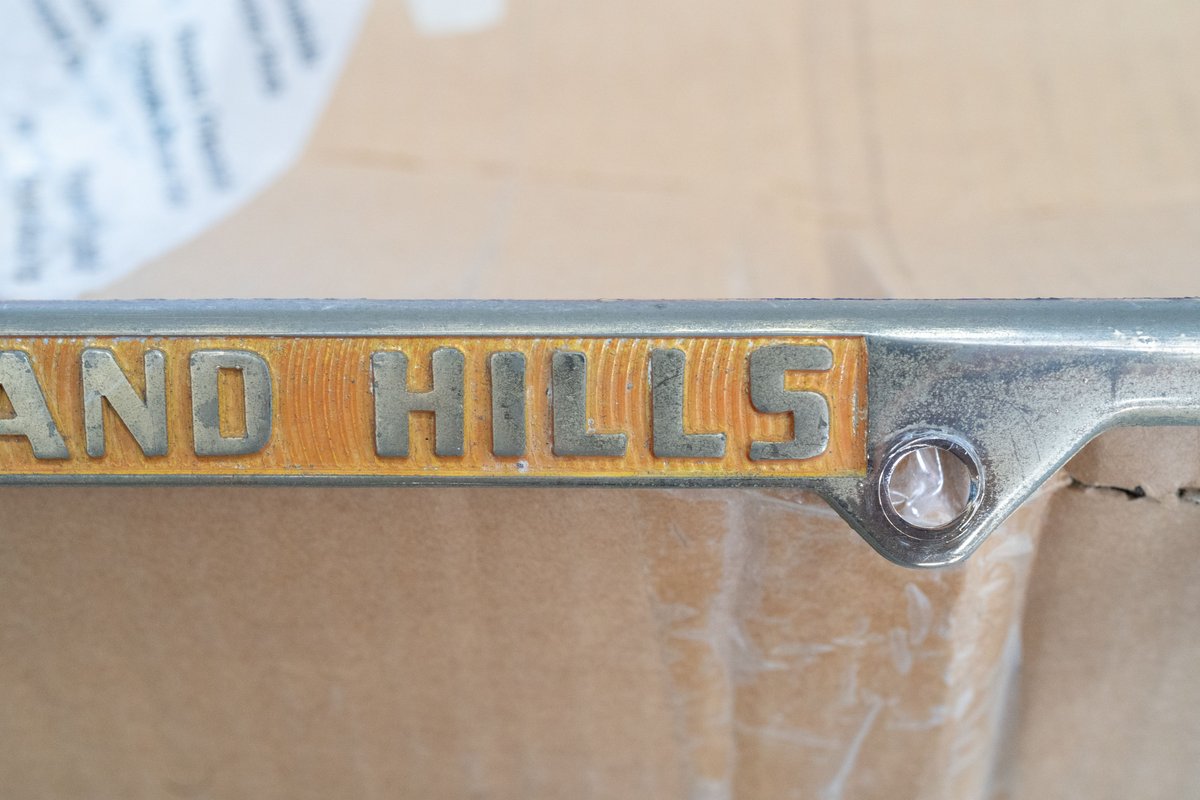 Close up of "GRAND HILLS" gold plate trim from a vehicle.
