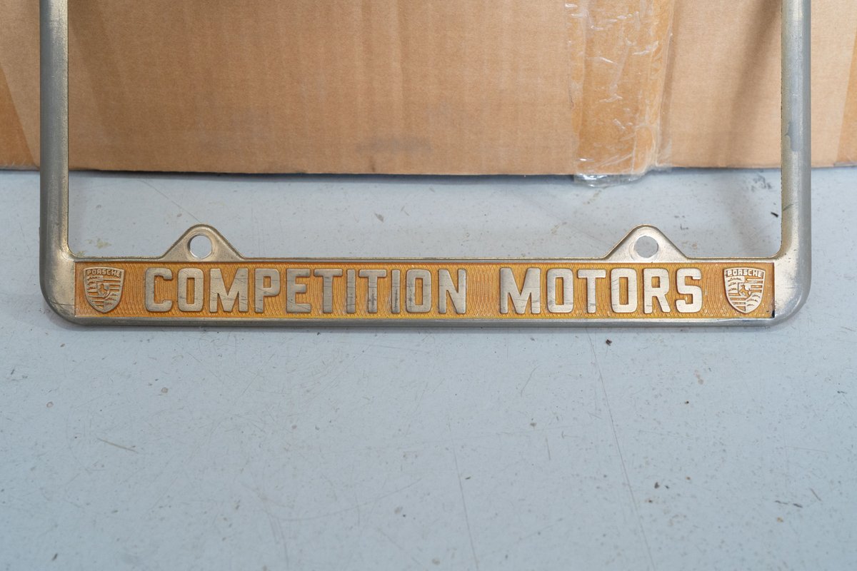 Vintage Porsche Competition Motors license plate frame with gold enamel trim.