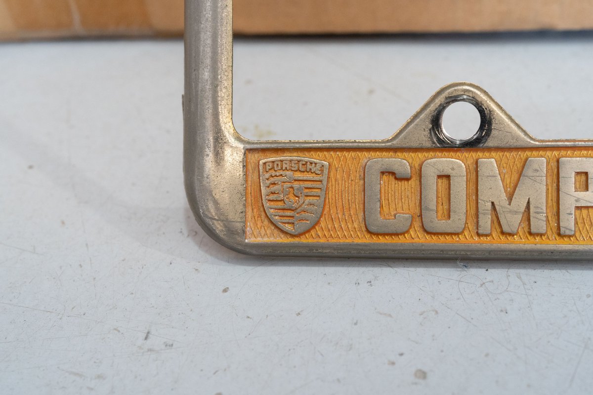 Gold Porsche Competition Motors license plate frame with embossed crest.