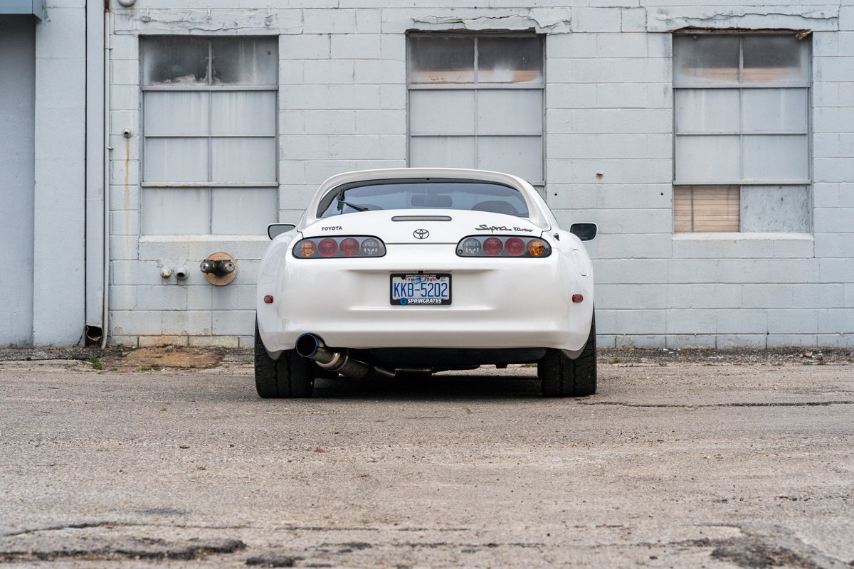 White 1994 Toyota Supra Targa, modified with an aftermarket exhaust and wide rear tires.