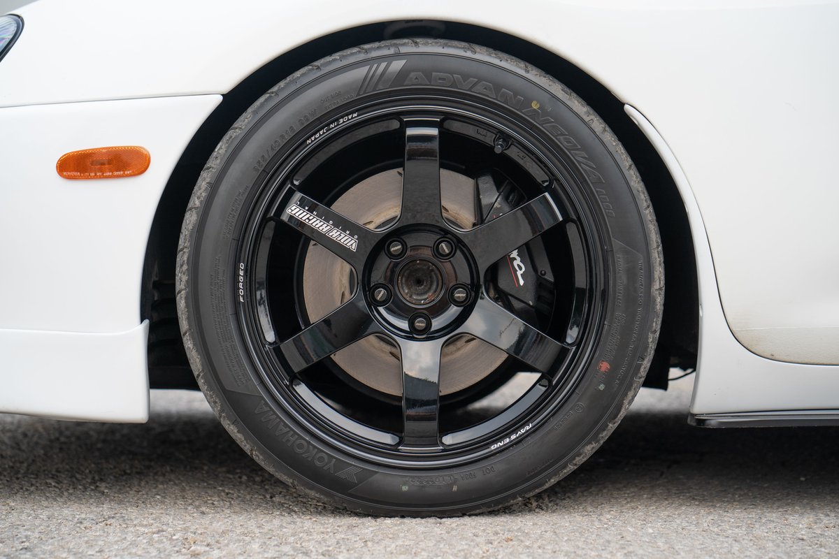Close-up of a white 1994 Toyota Supra's black 6-spoke TE37 rims and Yokohama Advan tires.