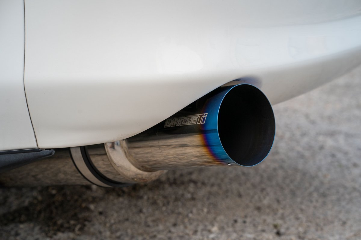 Close-up of a white 1994 Toyota Supra's burnt titanium exhaust tip.