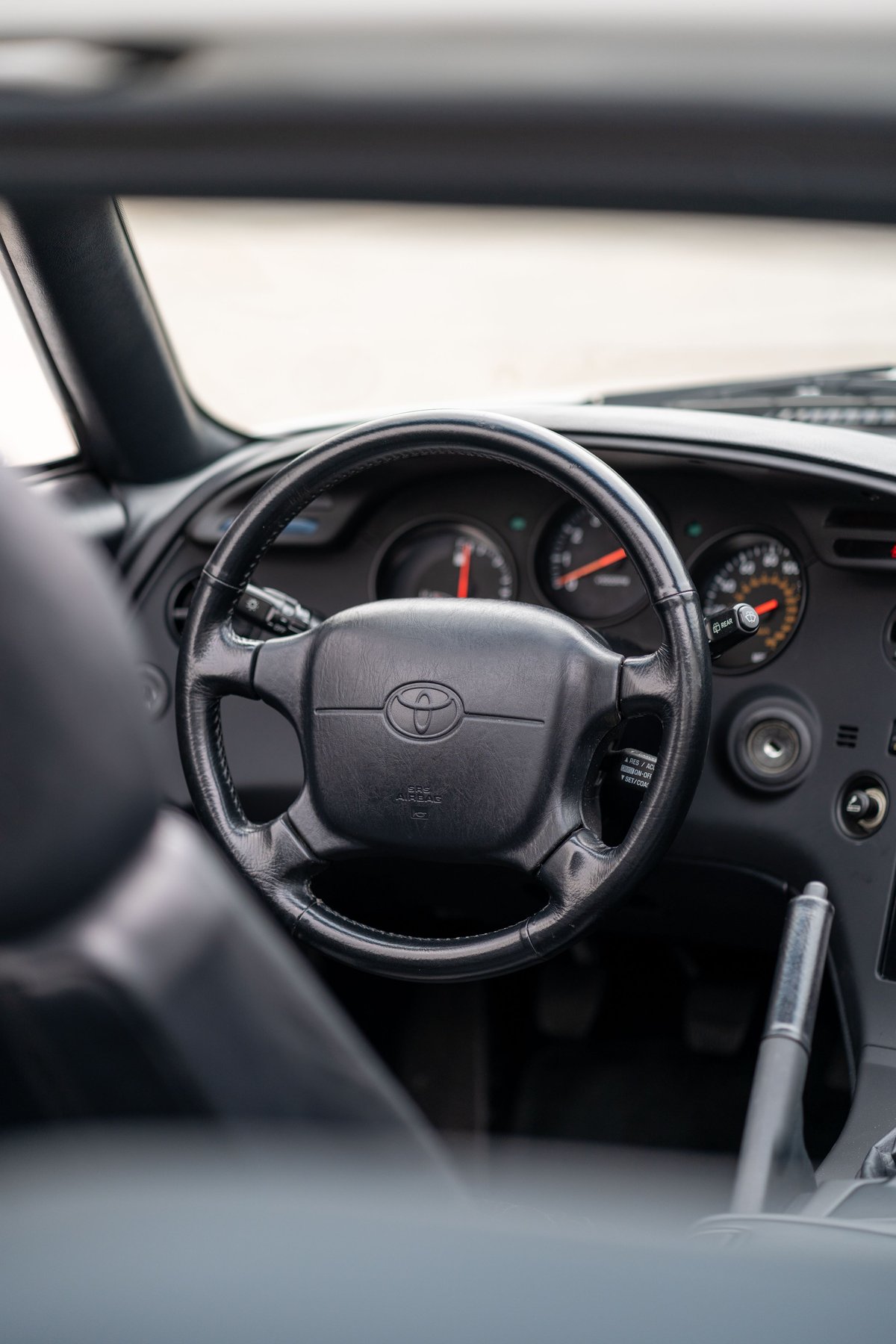 Interior shot of a white 1994 Toyota Supra T56 featuring its original steering wheel and dashboard.