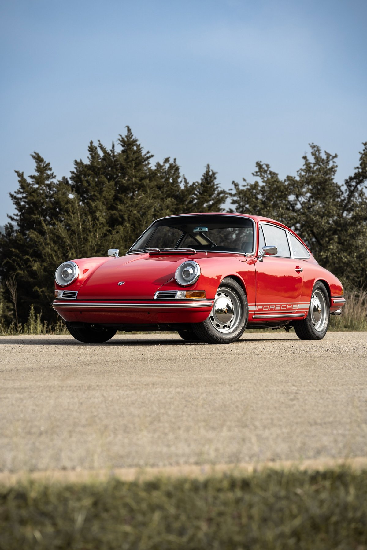 Front 3/4 view of a red 1967 Porsche 912 coupe with chrome trim and Fuchs wheels.