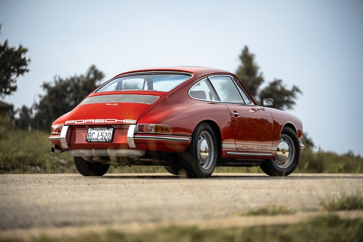 1967 Porsche 912 Coupe in Polo Red, rear 3/4 view, chrome trim, stock rims.