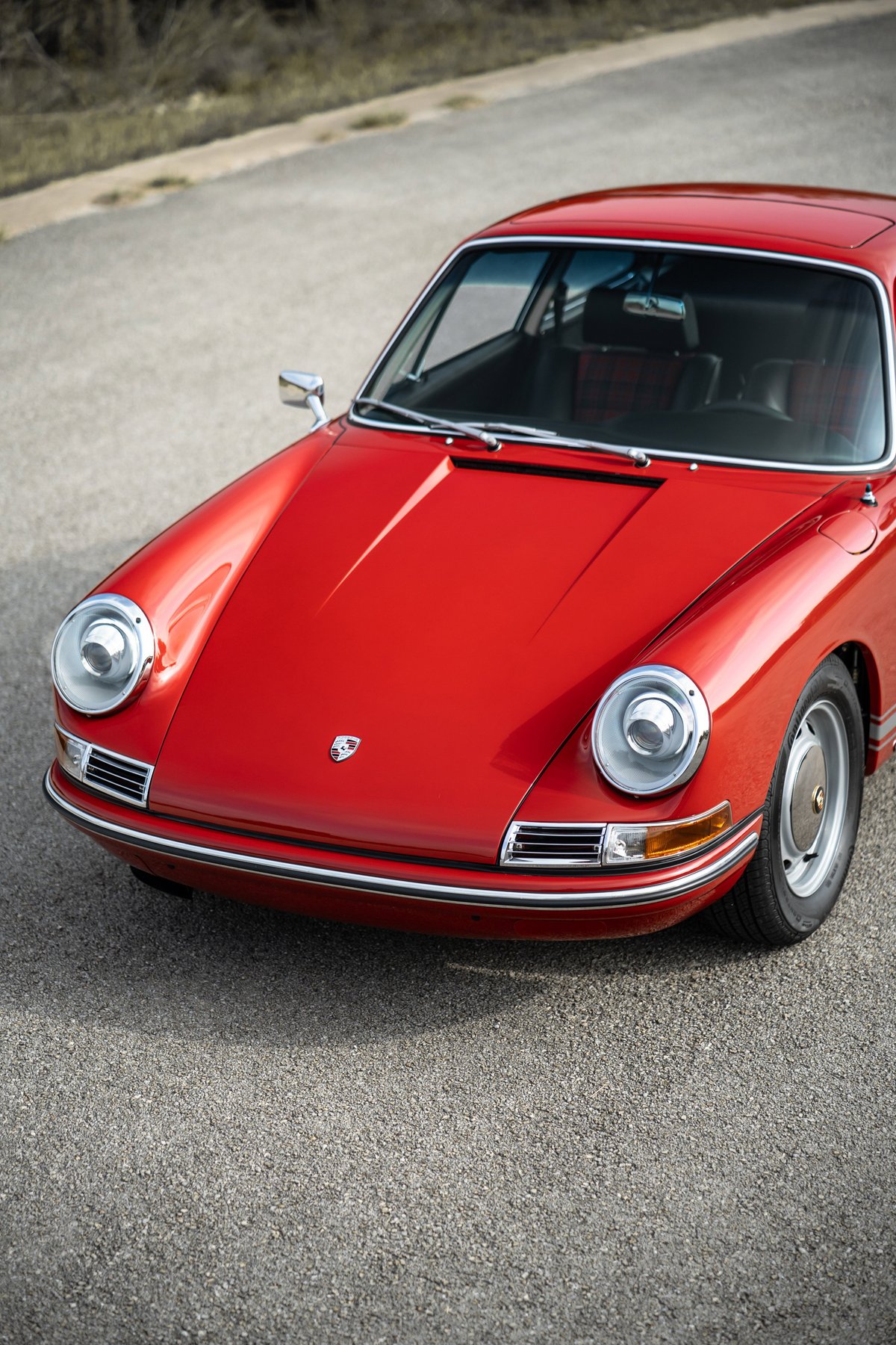 Front view of a red 1967 Porsche 912 Coupe with chrome trim and original rims.