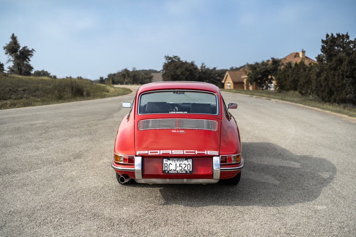 Rear view of a red 1967 Porsche 912 coupe with chrome trim and classic wheels.