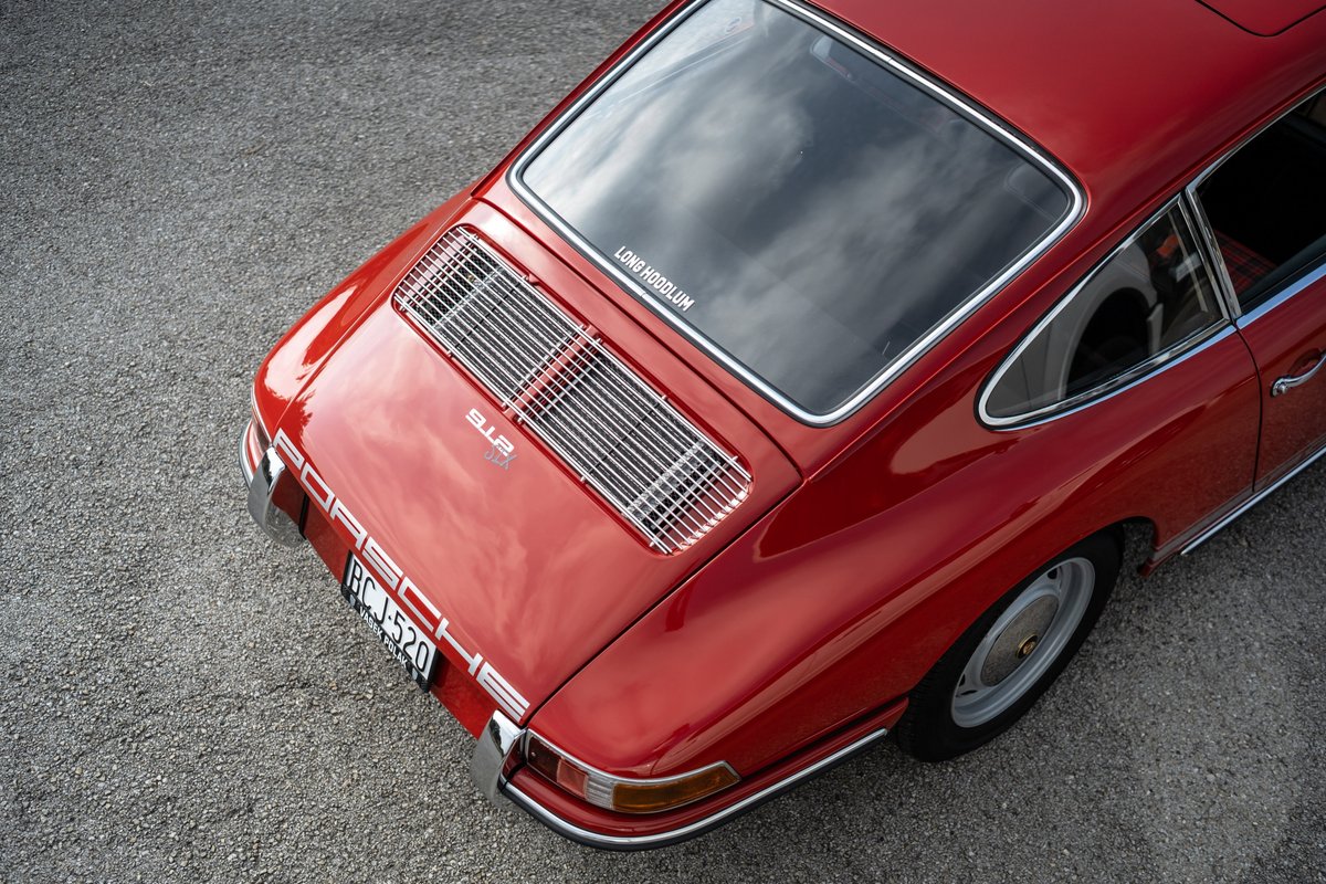 Rear view of a red 1967 Porsche 912 coupe with chrome trim and a rear engine grille.