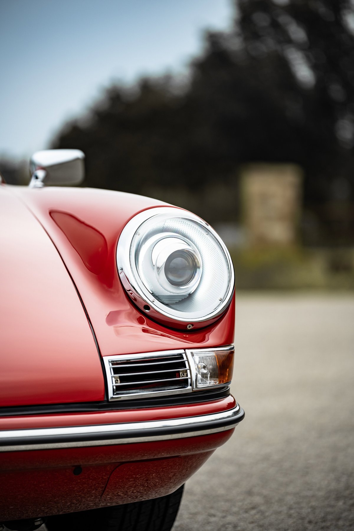 Close-up of a red 1967 Porsche 912 coupe's front fender, headlight, and bumper.