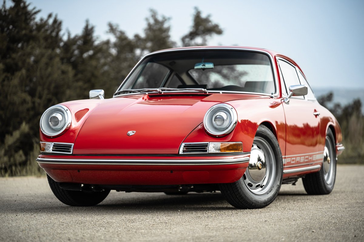 Red 1967 Porsche 912 Coupe with chrome trim and silver hubcap rims.