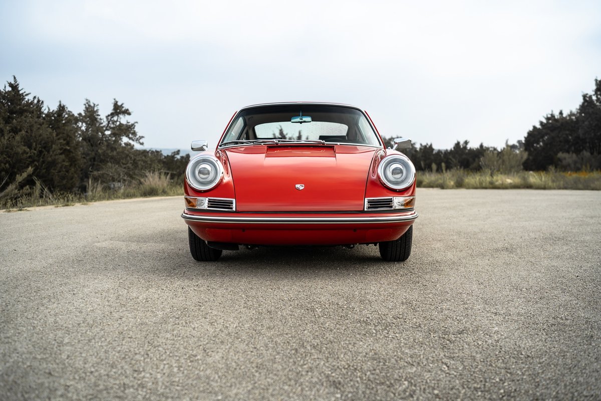 Front view of a red 1967 Porsche 912 coupe with chrome trim and classic round headlights.