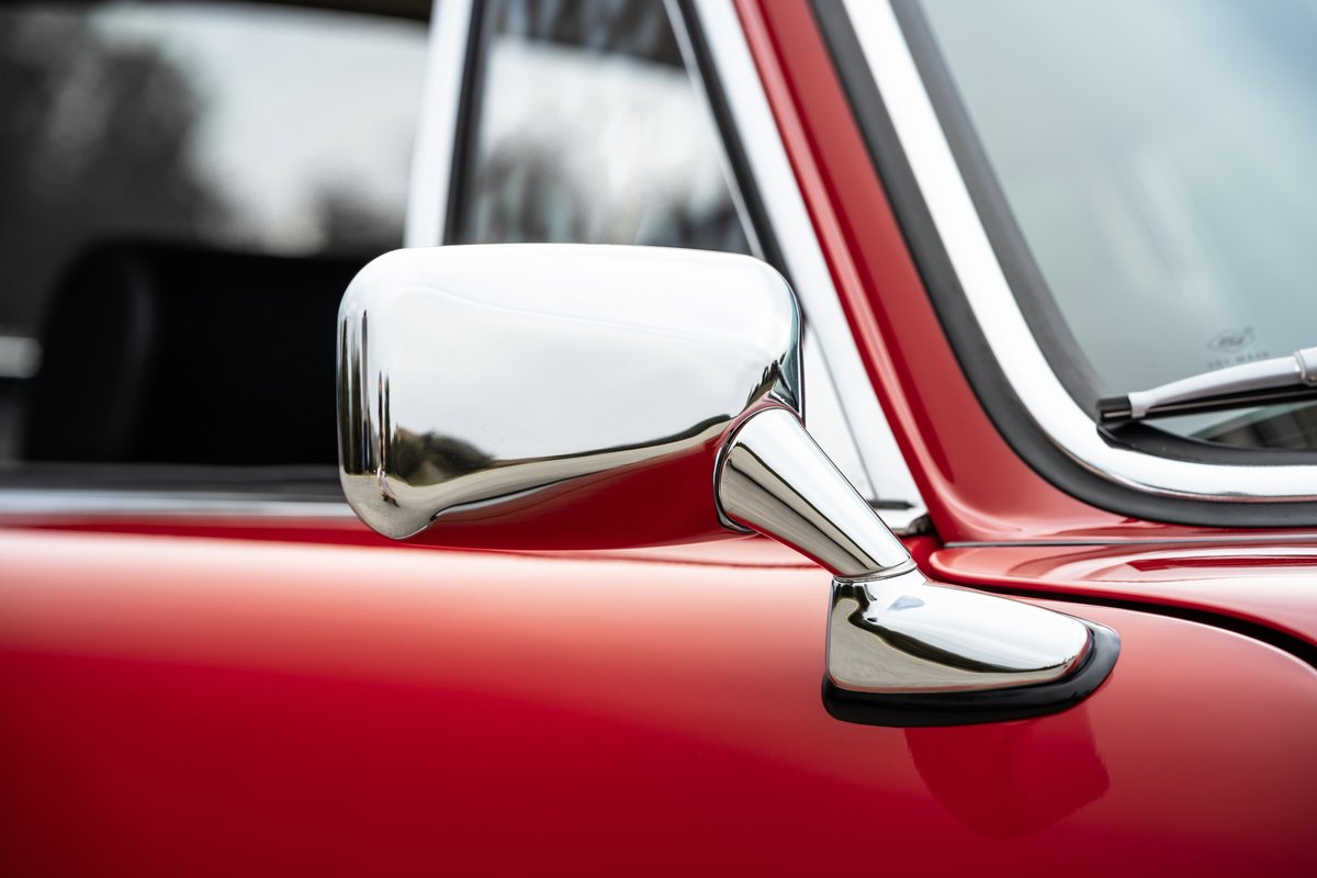 1967 Porsche 912 in Polo Red, showcasing a classic chrome side mirror.