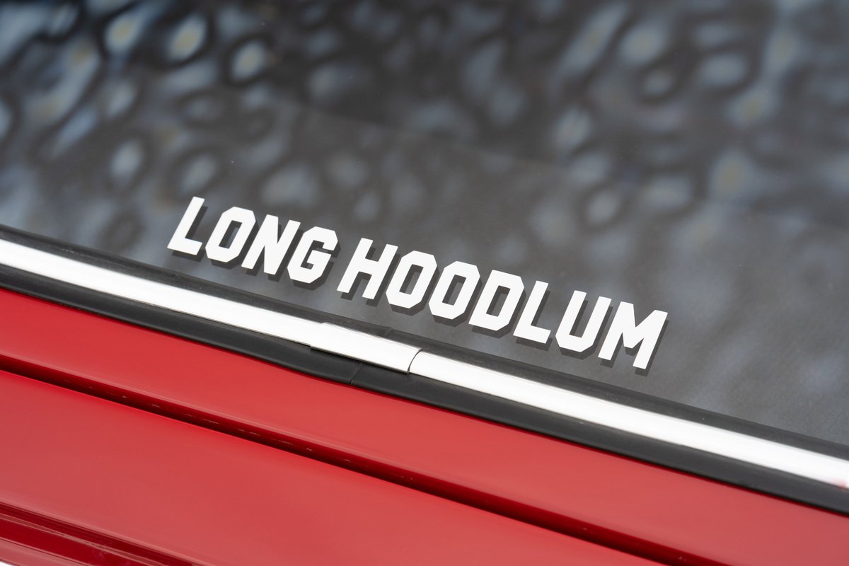 White "Long Hoodlum" decal on the window of a red 1967 Porsche 912 coupe.
