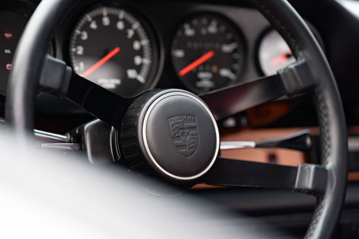 Classic Porsche 912 steering wheel with crest and analog gauges.