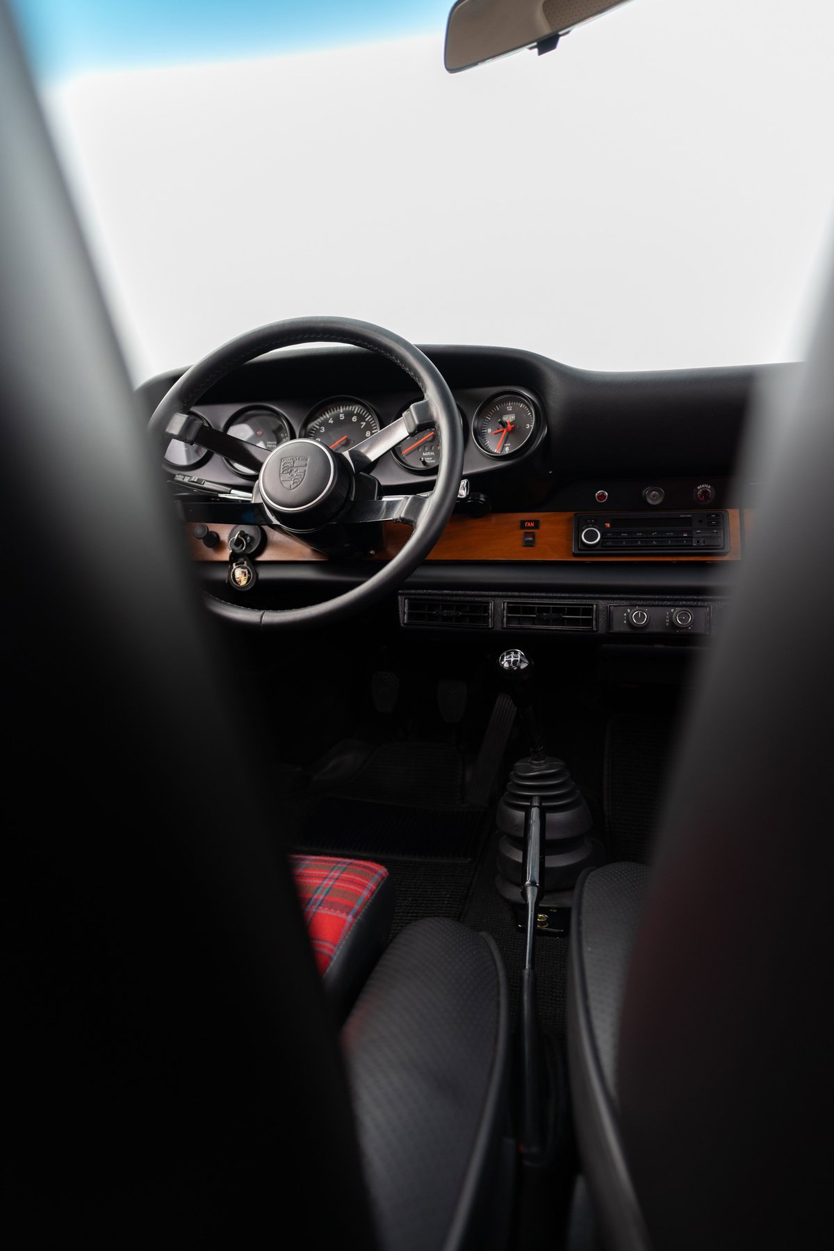 Interior of a red 1967 Porsche 912 coupe with tartan seat inserts and a wood trim dashboard.