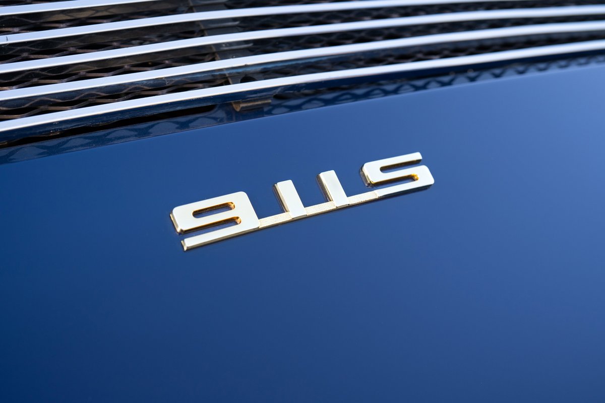 Gold "911S" badge on the dark blue metallic hood of a 1969 Porsche 911S.
