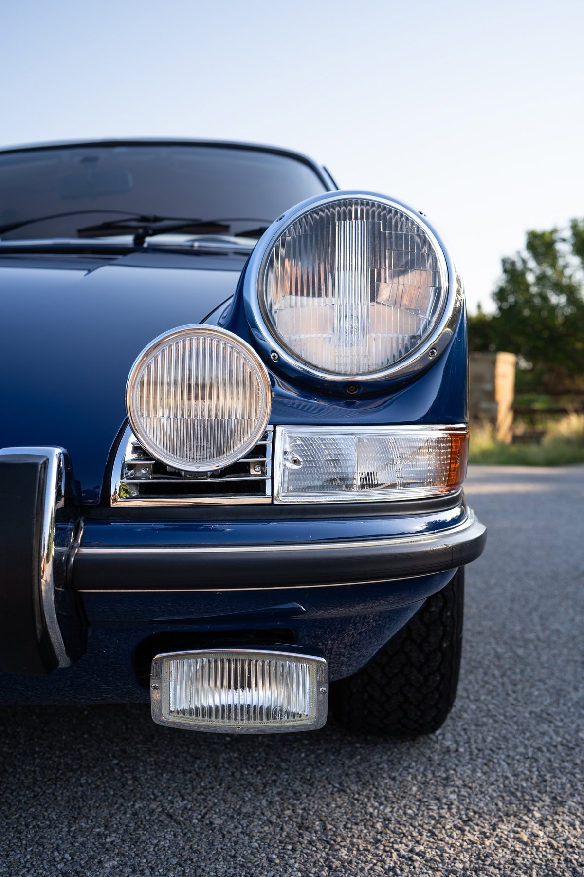 Close-up of a blue 1969 Porsche 911S front bumper, headlights, and grille.