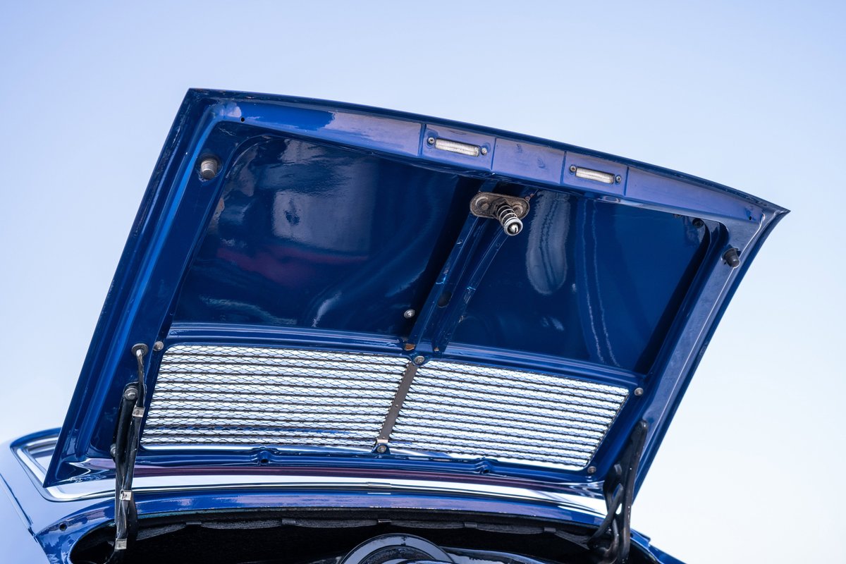 Open hood of a blue 1969 Porsche 911S shows a satin grille and interior detail.