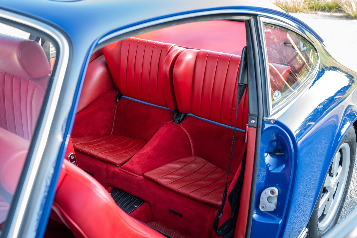 Blue 1969 Porsche 911S coupe interior with red leather seats and carpeting.