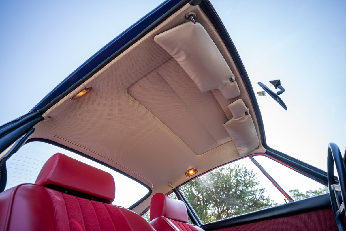 Interior of a 1969 Porsche 911S. Red seats, tan headliner, sunroof, and rearview mirror.
