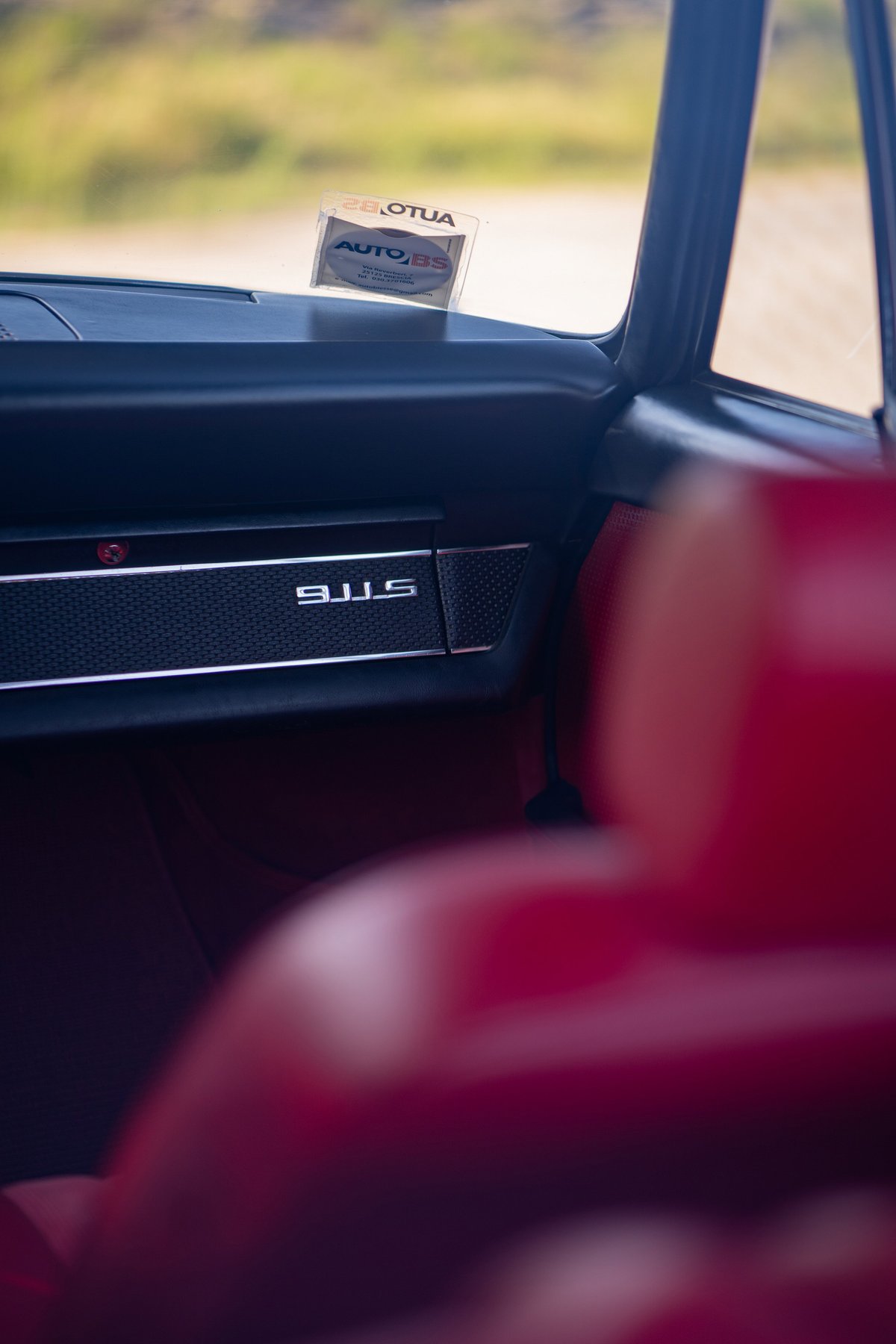 Interior shot of a blue 1969 Porsche 911S with red seats and chrome trim.