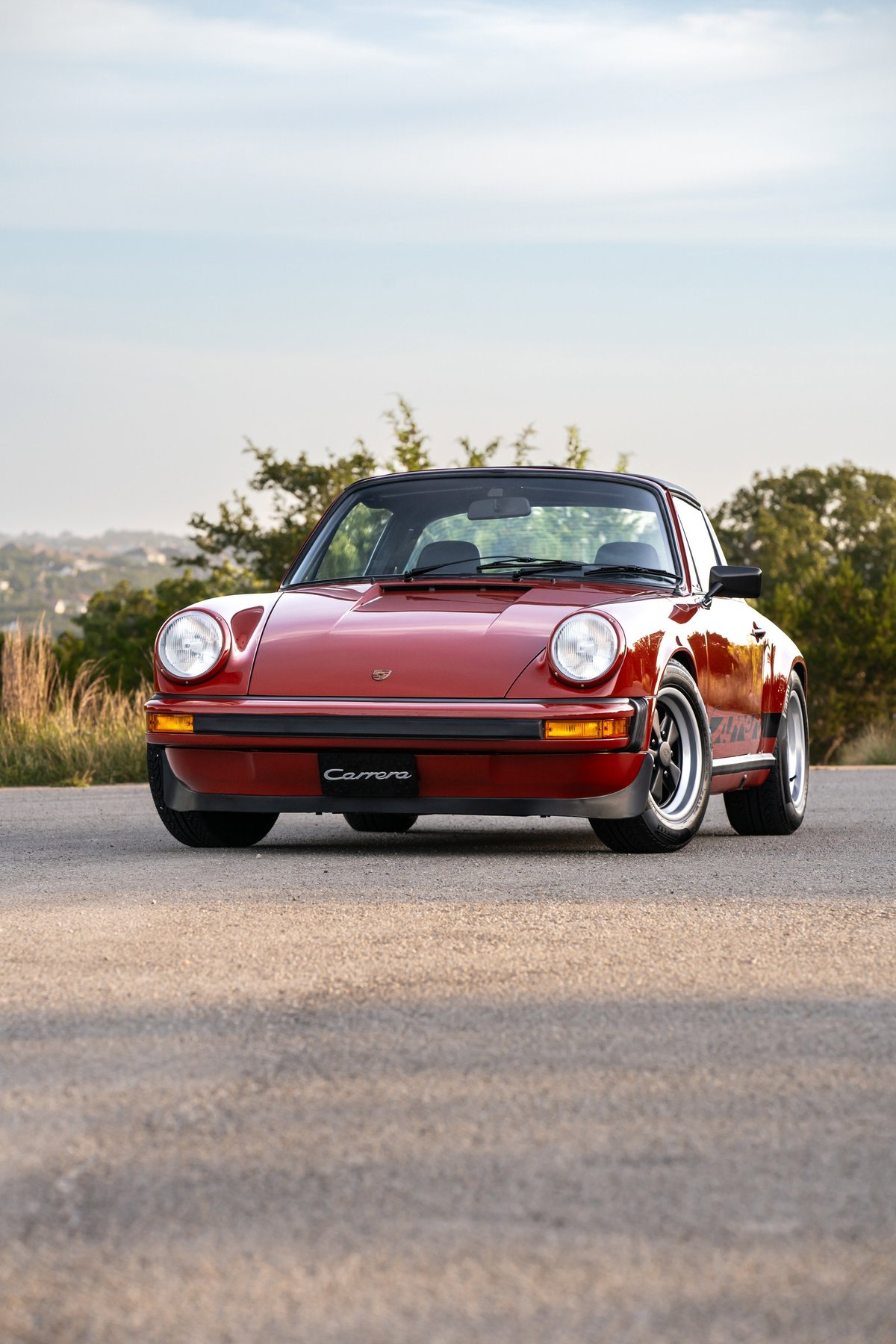 Front view of a red 1974 Porsche 911 Carrera Targa with black trim and classic alloy rims.