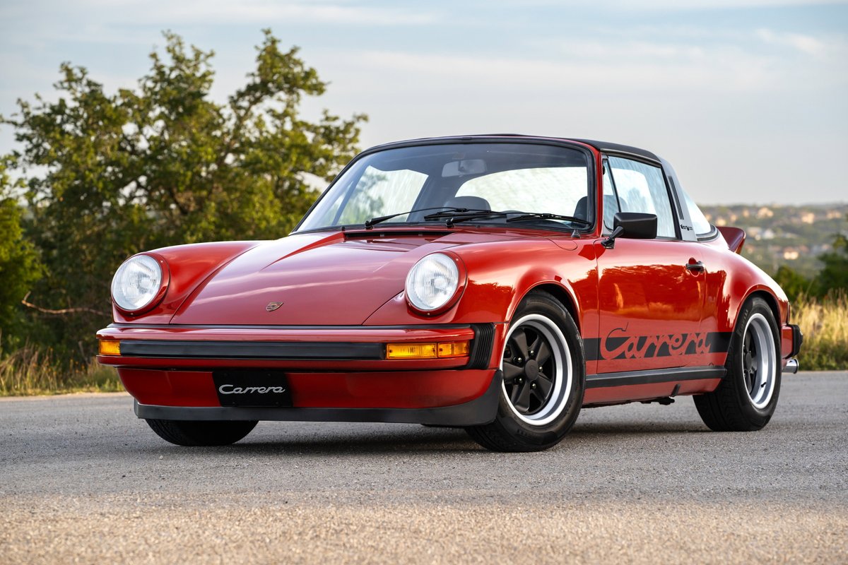 Red 1974 Porsche 911 Carrera Targa with black stripe livery and black Fuchs rims.