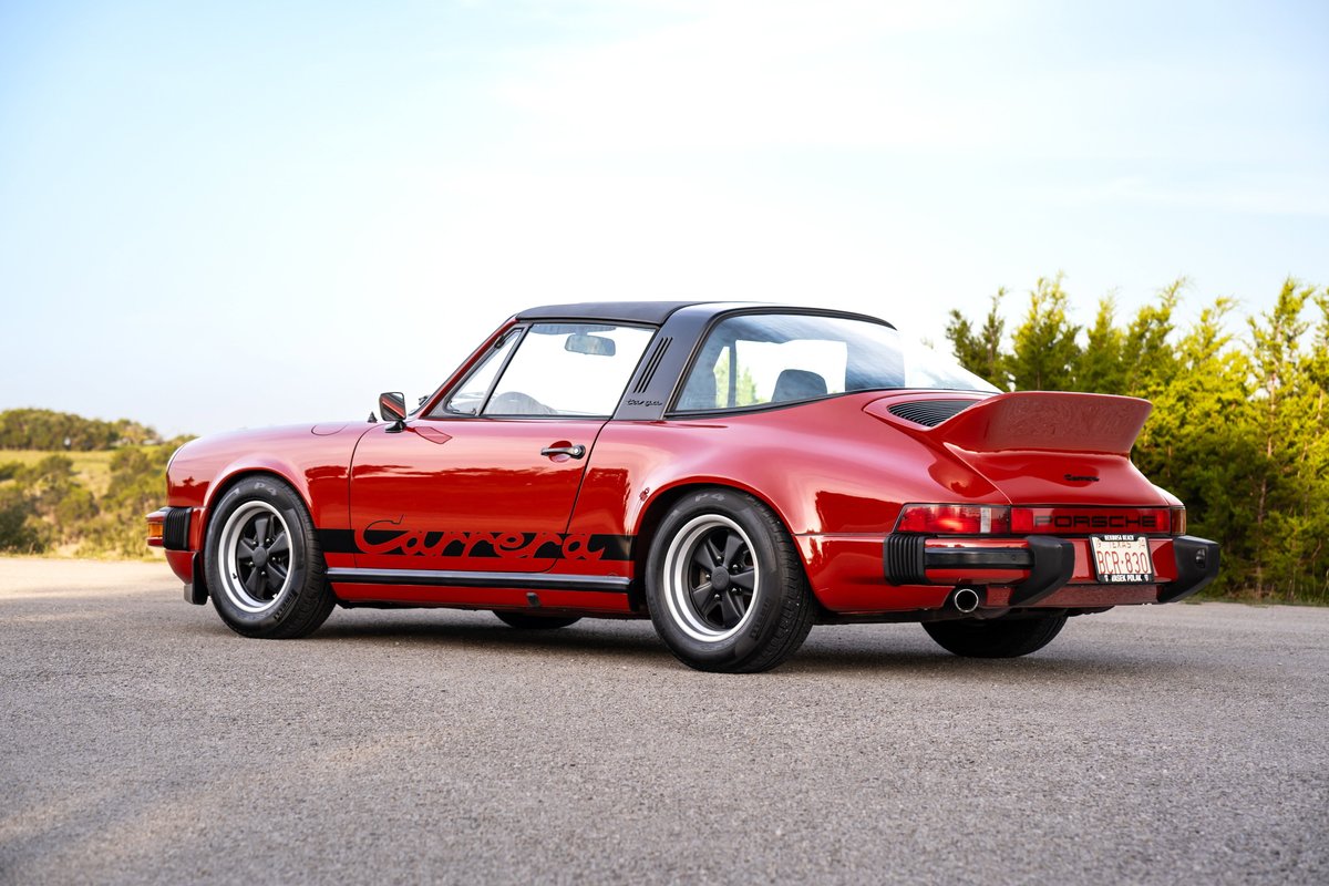 Red 1974 Porsche 911 Carrera Targa with black trim, gold lettering, and Fuchs rims.
