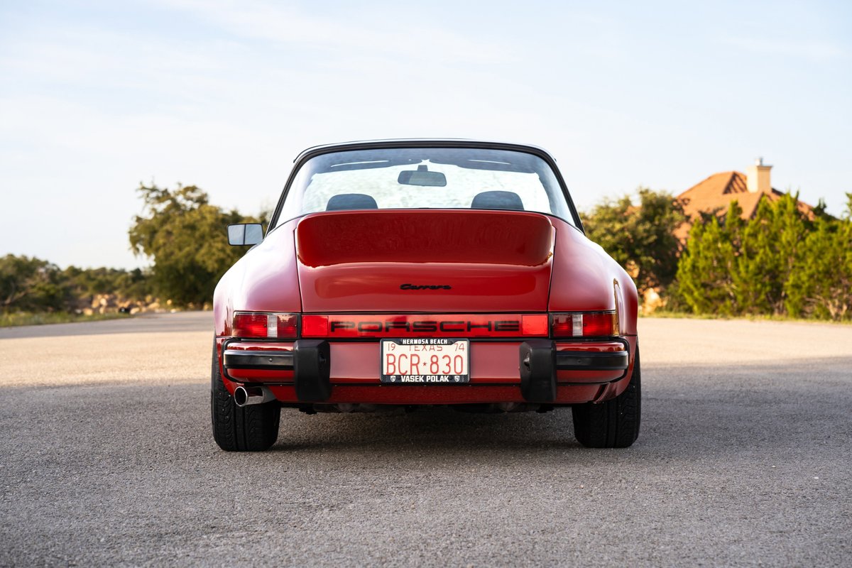 Rear view of a red 1974 Porsche 911 Carrera Targa, showing off its classic taillights and bumper trim.