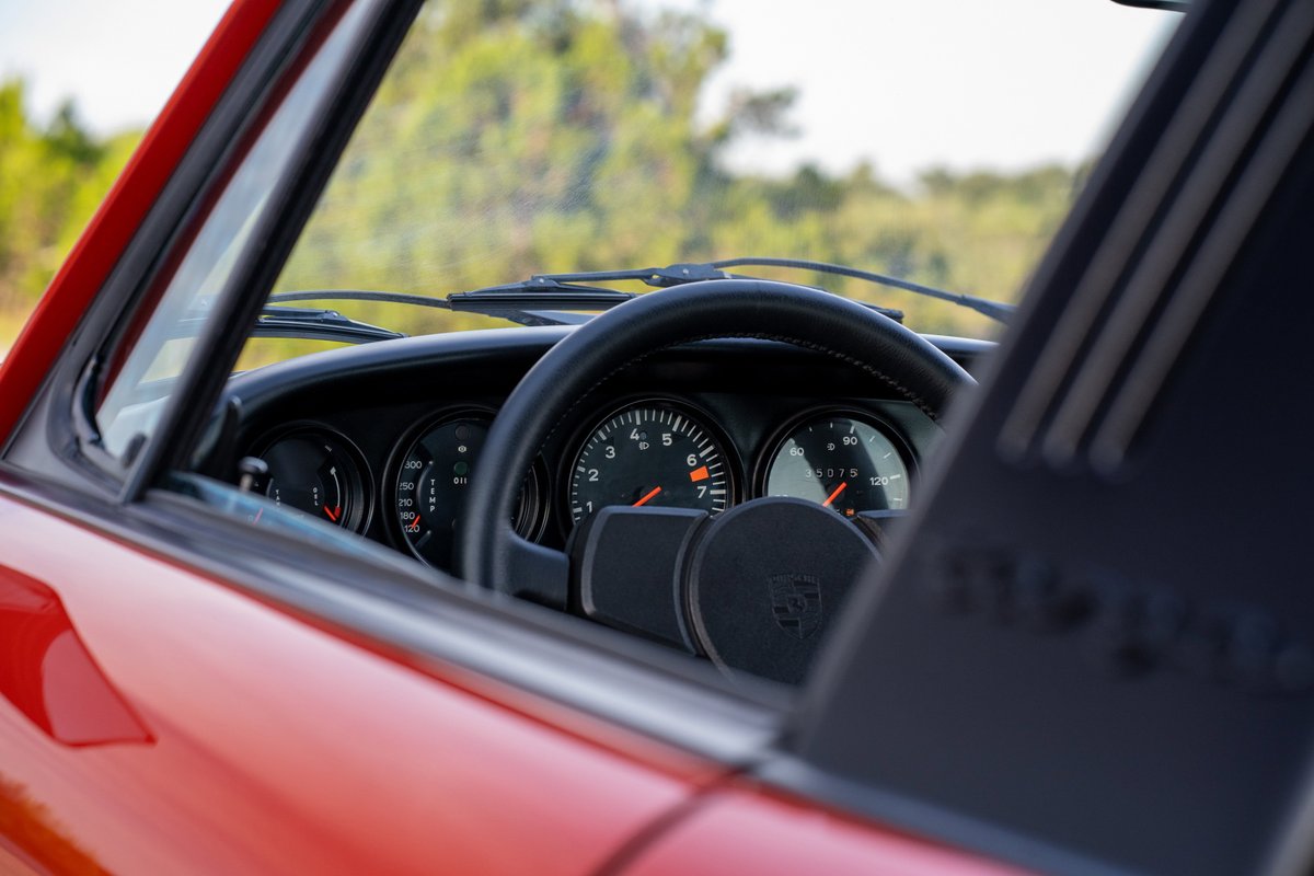 Red 1974 Porsche 911 Carrera Targa interior detail, showing gauges & steering wheel.
