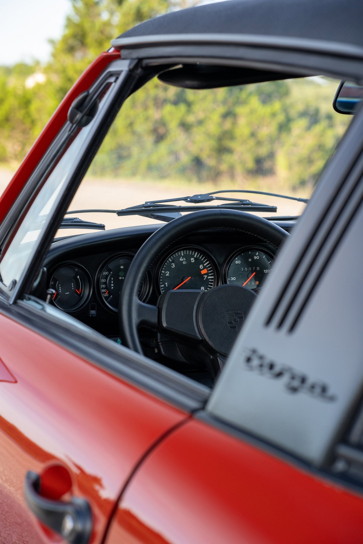 Red 1974 Porsche 911 Carrera Targa interior with classic gauges and "Targa" badging.