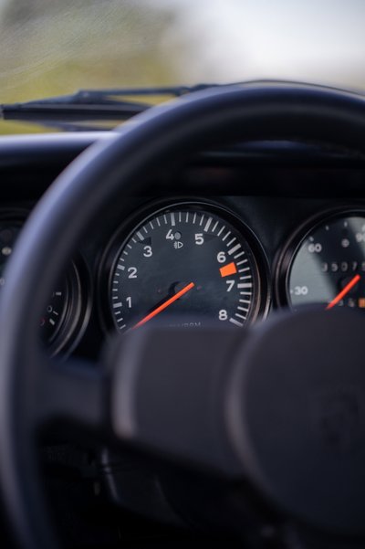 Close up of a red 1974 Porsche 911 Carrera Targa dashboard with tachometer.