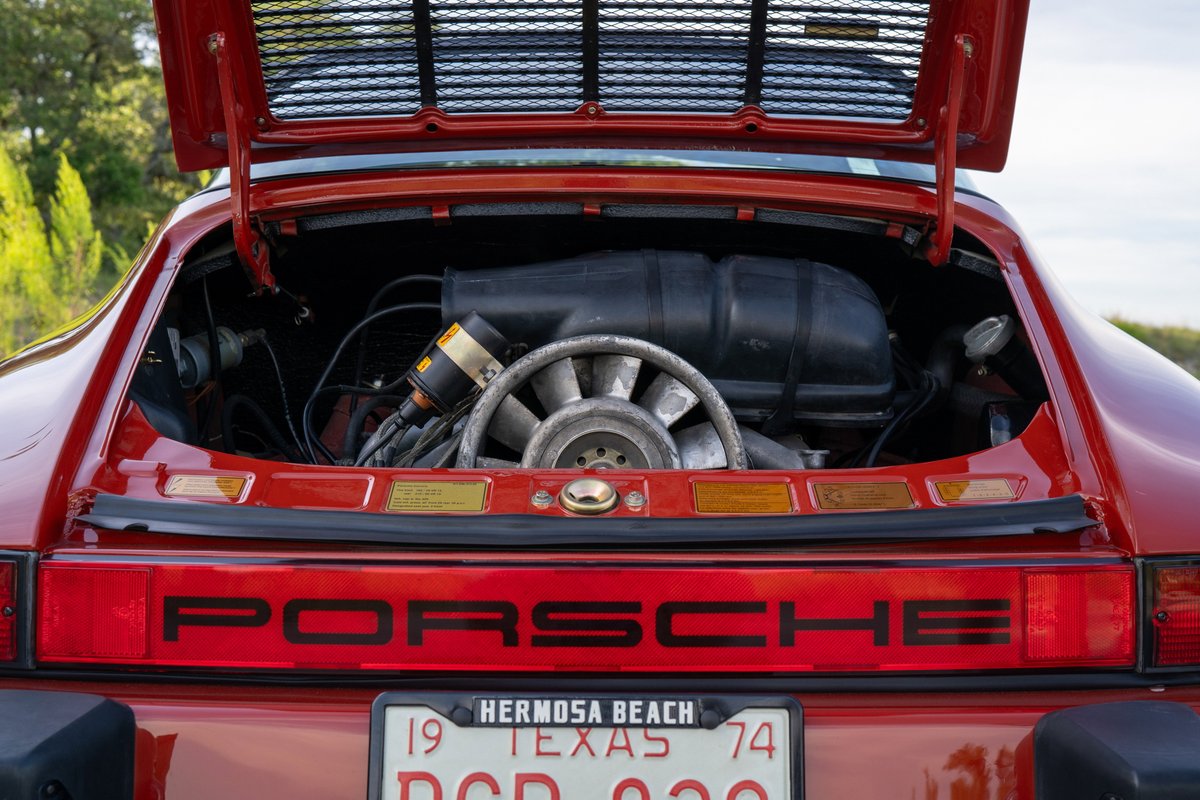 Red 1974 Porsche 911 Carrera Targa engine bay with air-cooled flat-six, fan, and distributor.