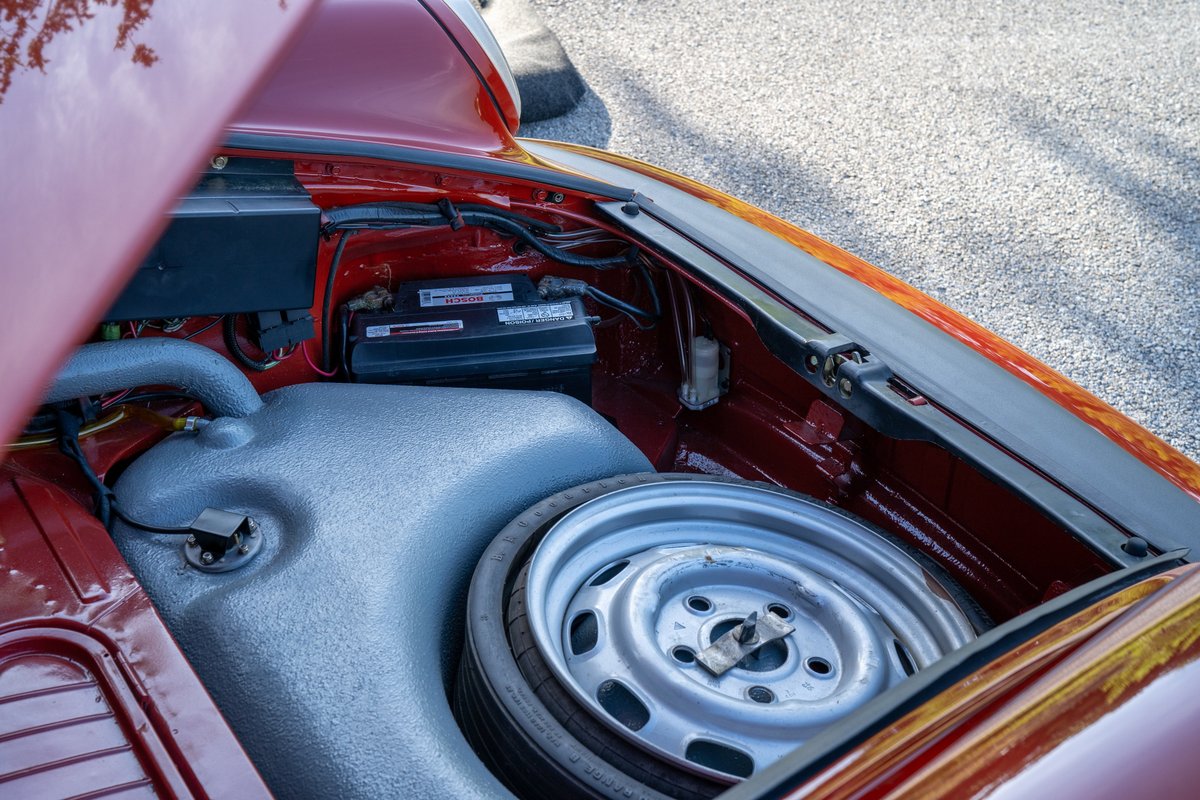 Red 1974 Porsche 911 Carrera Targa spare tire well with battery and fuel tank.