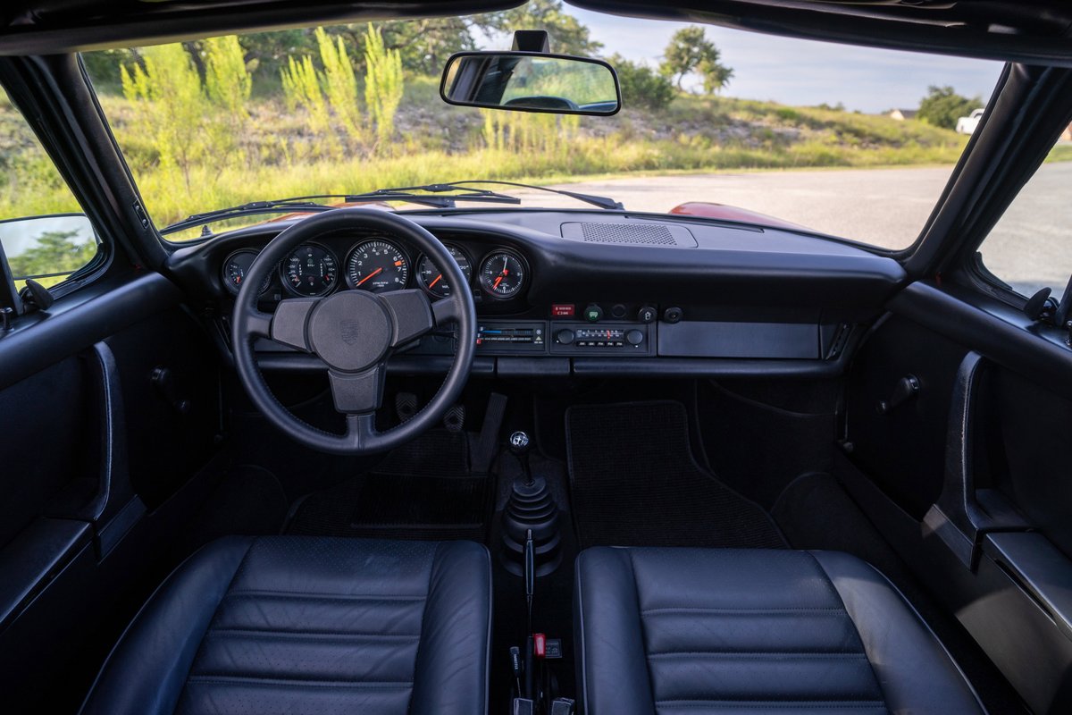 1974 Porsche 911 Carrera Targa interior with black leather seats and a four-spoke steering wheel.