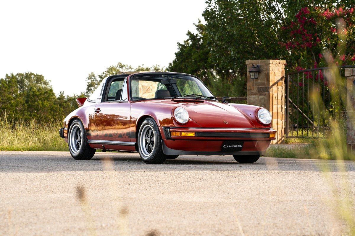 1974 red Porsche 911 Carrera Targa with Fuchs wheels, parked outdoors.