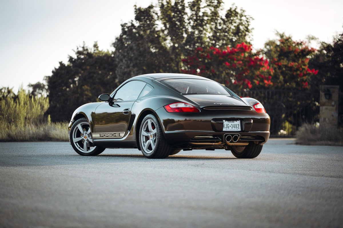 Rear view of a Macadamia Metallic 2008 Porsche Cayman S with silver rims and Porsche livery.