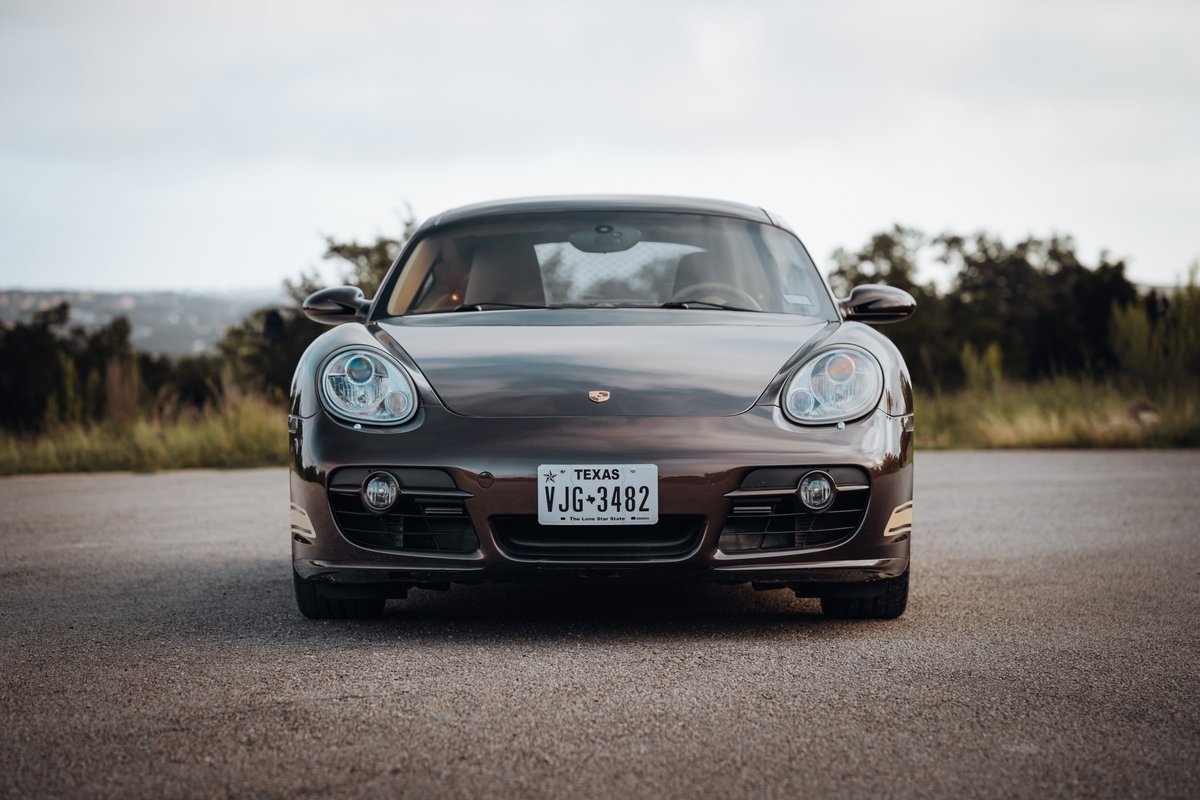 Front view of a Macadamia Metallic 2008 Porsche Cayman S with chrome rims parked on asphalt.