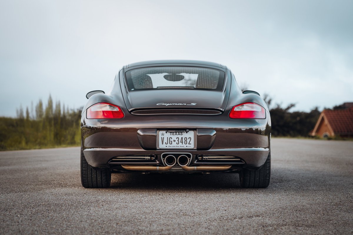 Rear view of a Macadamia Metallic 2008 Porsche Cayman S with quad exhaust tips.