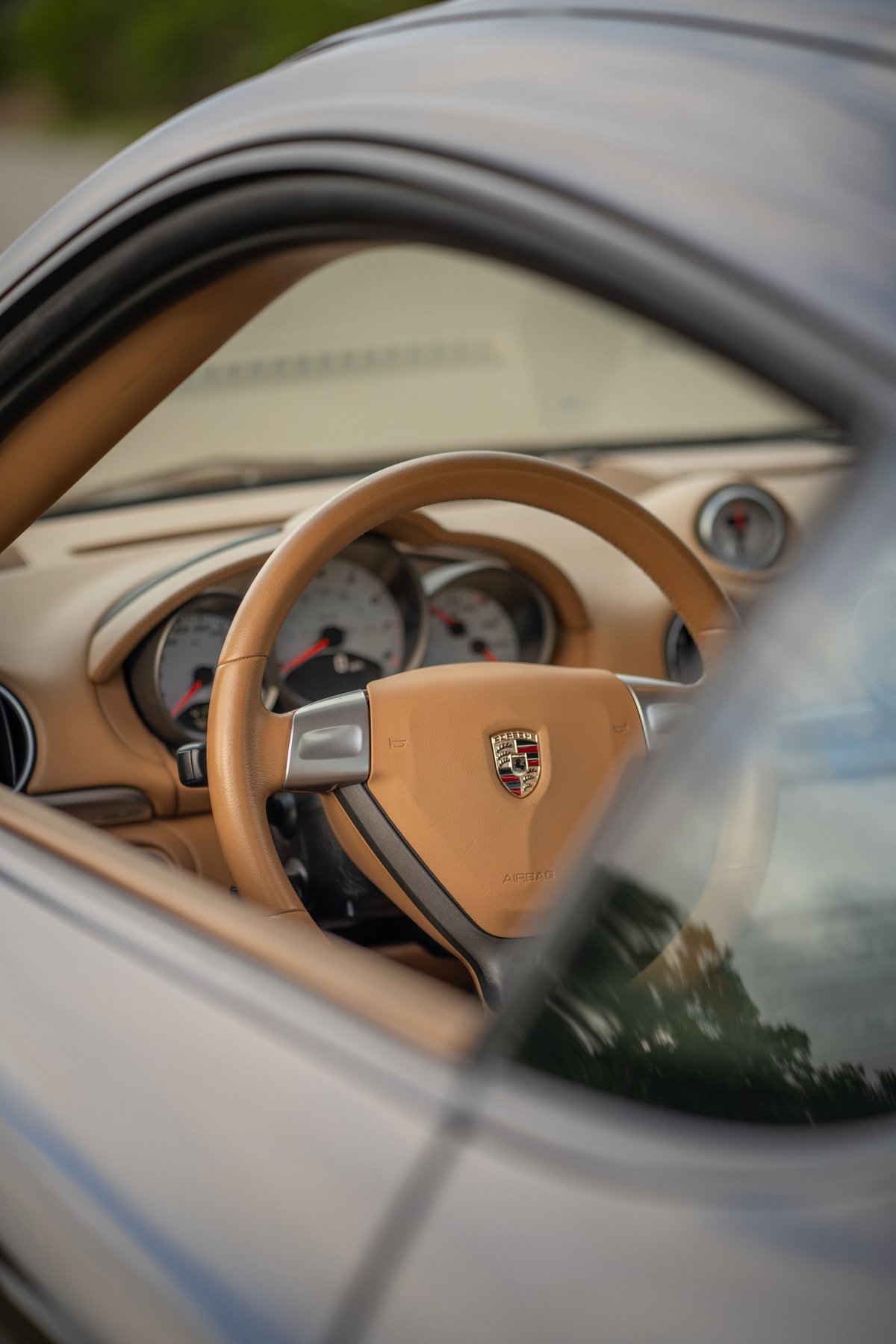 Interior view of a tan 2008 Porsche Cayman S with a tan steering wheel and dashboard.