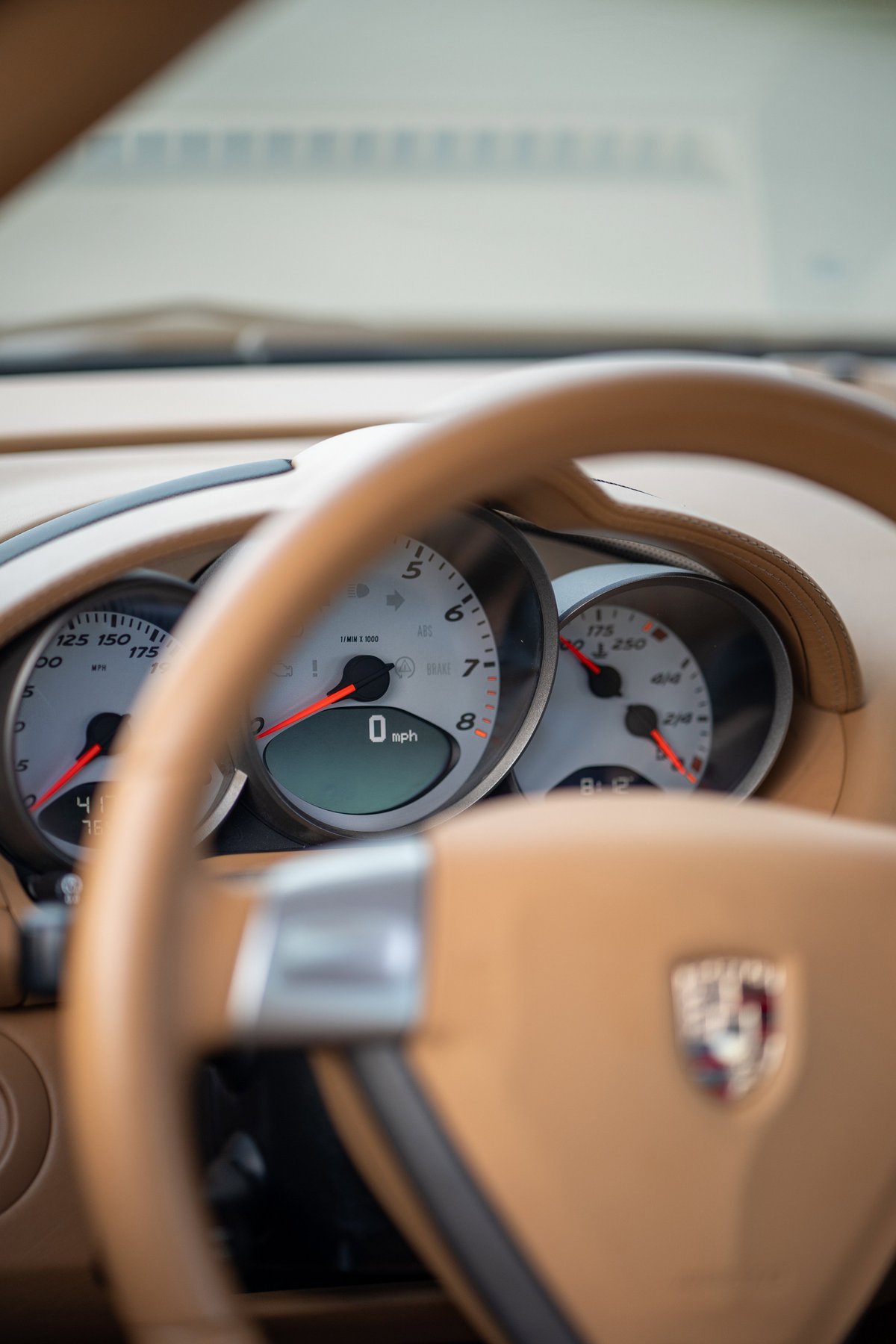 2008 Porsche Cayman S dashboard with tan leather trim and analog gauges.