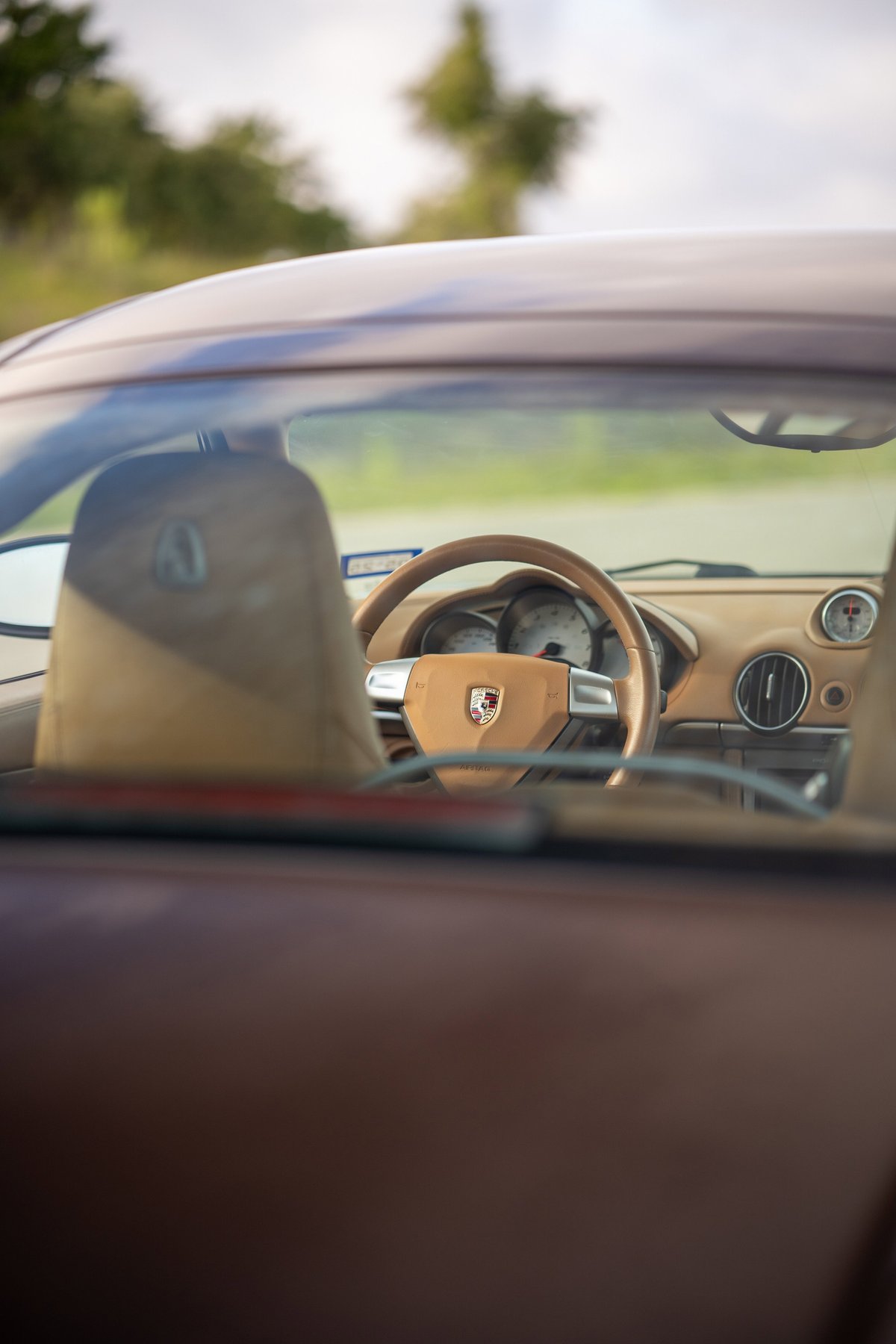 2008 Porsche Cayman S interior with tan leather trim and chrome accents on the steering wheel.