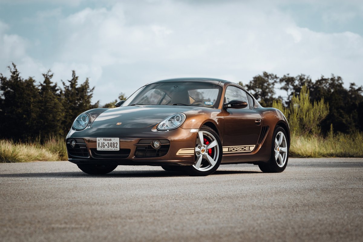 Brown 2008 Porsche Cayman S with gold "Porsche" livery and red brake calipers.