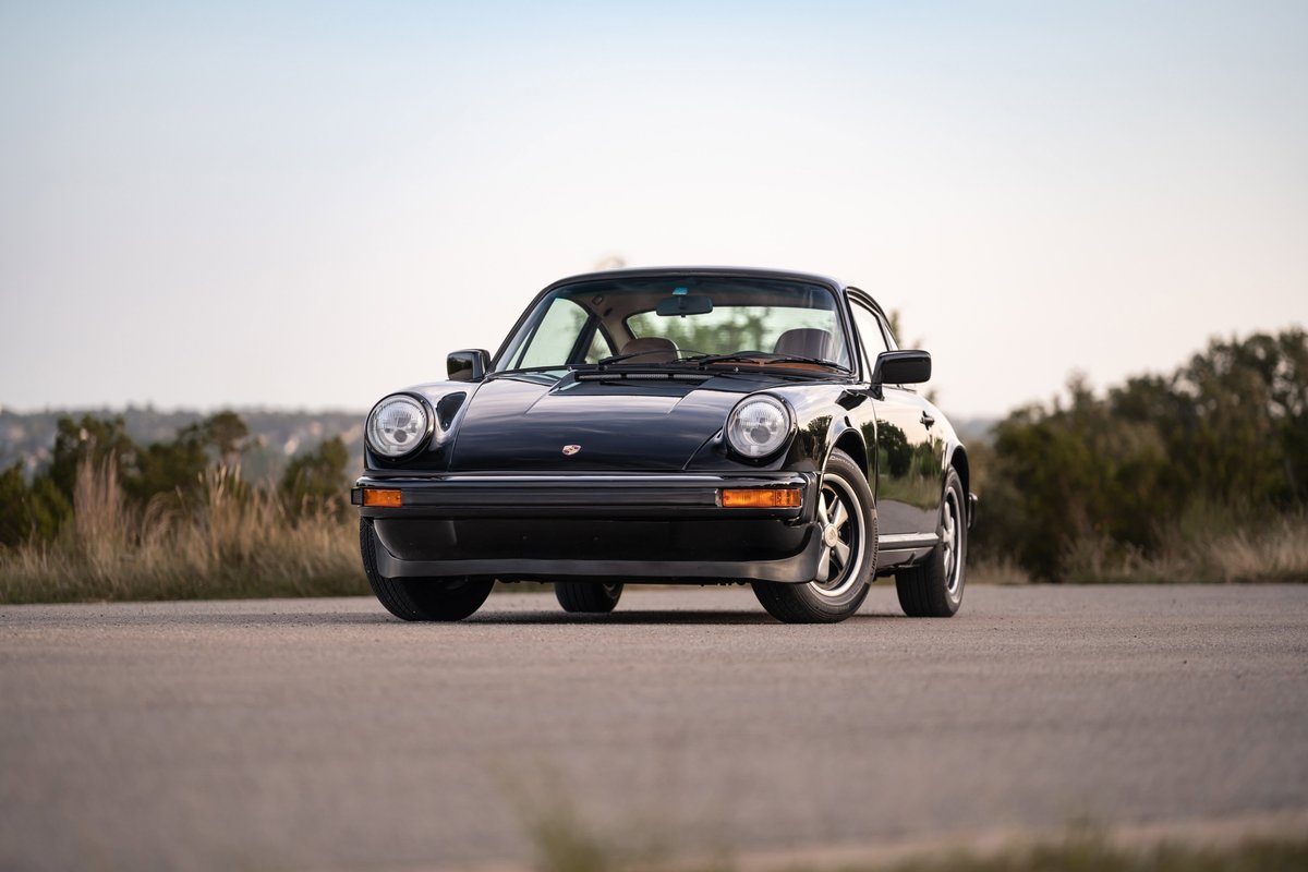 Front view of a black 1976 Porsche 911S with Fuchs rims and chrome trim.