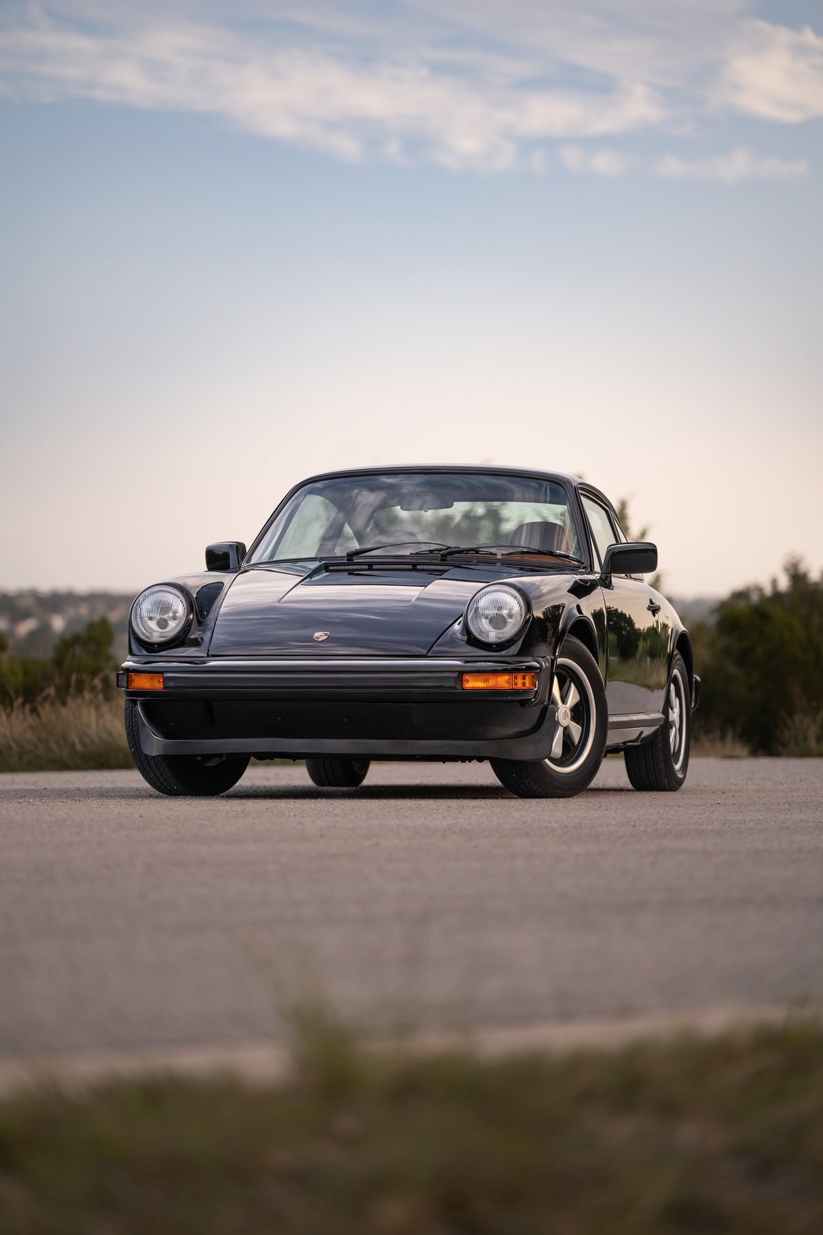 Front view of a black 1976 Porsche 911S with Fuchs wheels.
