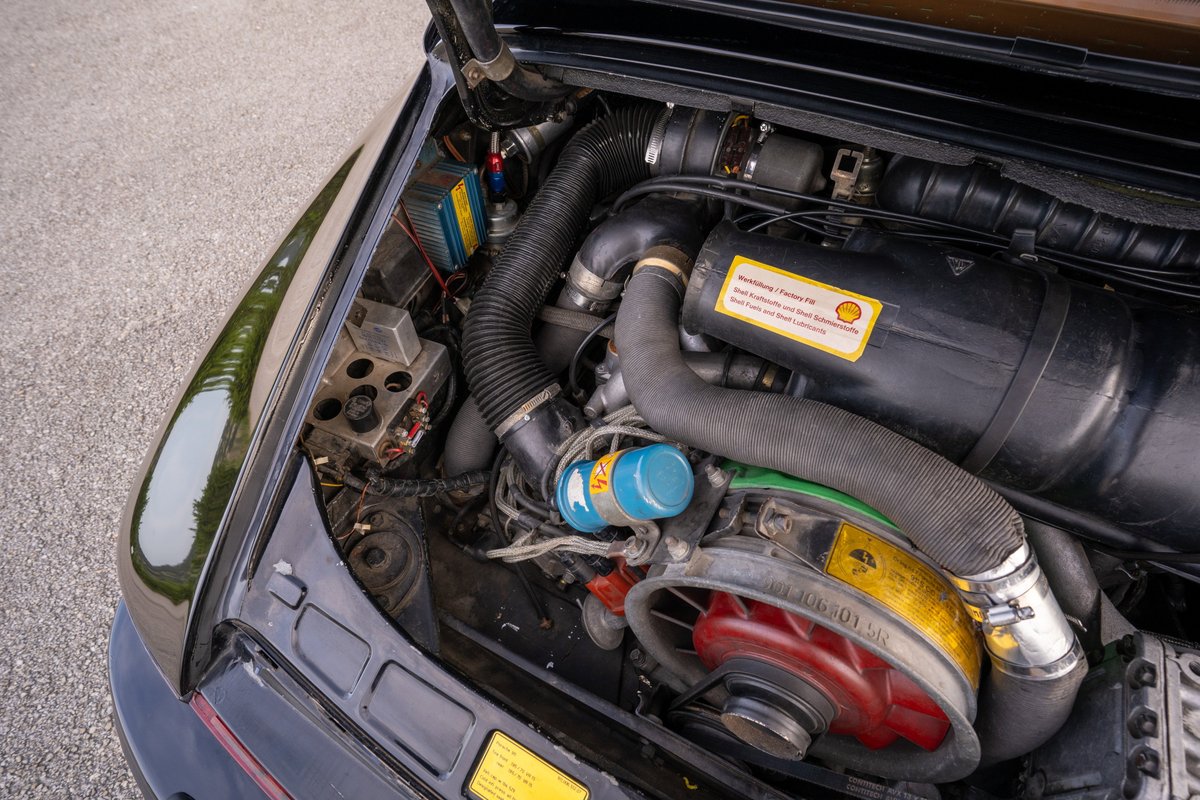 Close-up of a black 1976 Porsche 911S Sportomatic engine bay with a blue oil cooler.